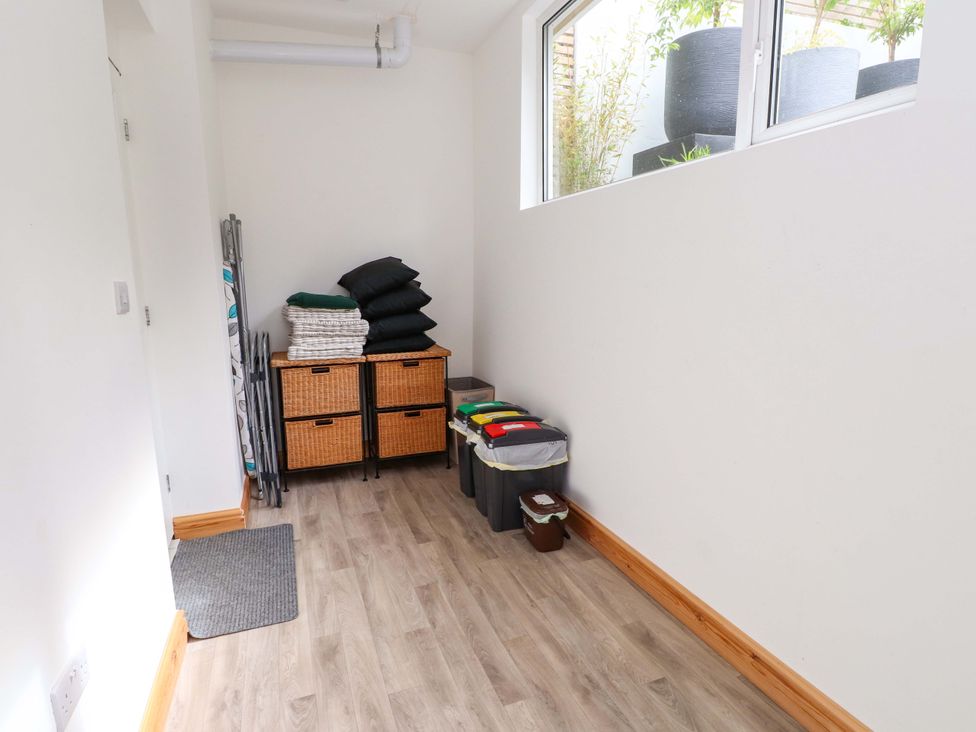 A utility room with storage bins and folded towels at Hendre in Menai Bridge