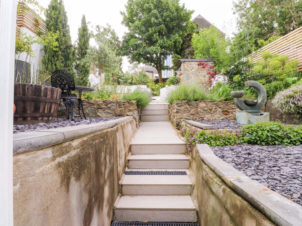 A garden with steps leading up and a sculpture at Hendre in Menai Bridge