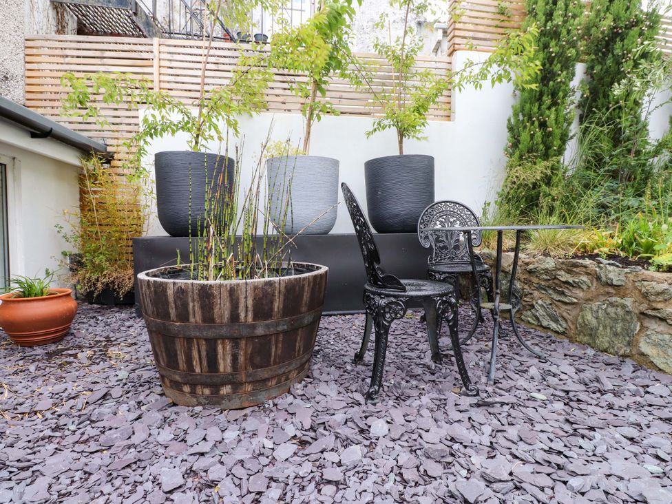 A garden with a wooden planter and a black chair at Hendre Menai Bridge
