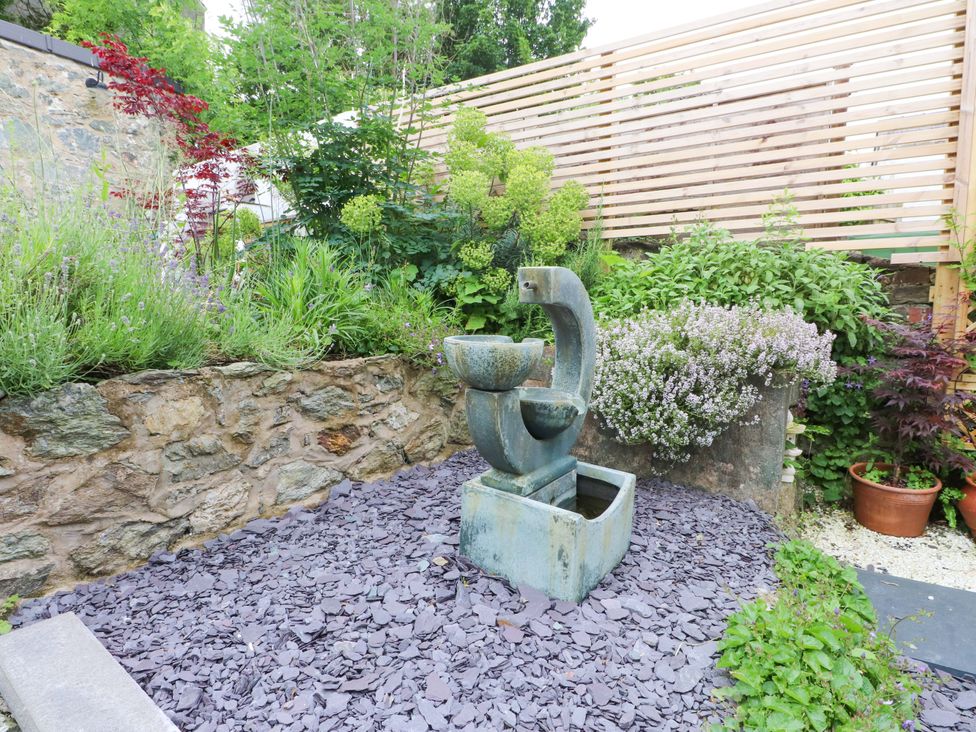 A garden with a fountain and various plants at Hendre in Menai Bridge
