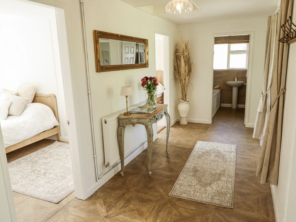 A hallway with a mirror and table at Lake View Cottage in Well near Alford