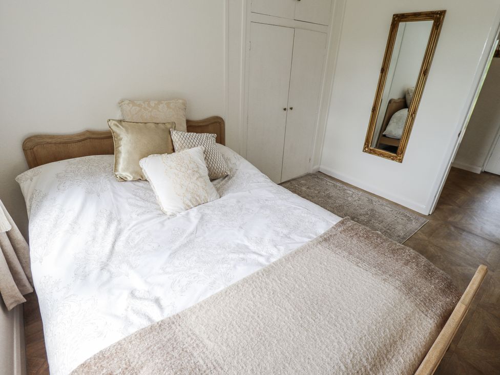 A bedroom with a bed and mirror at Lake View Cottage Well near Alford