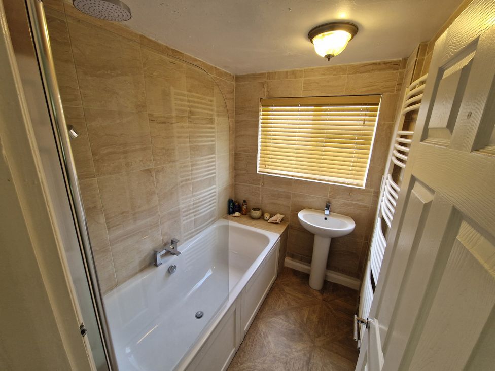 A bathroom with a bathtub, wash basin, and towel radiator at Lake View Cottage in Well near Alford