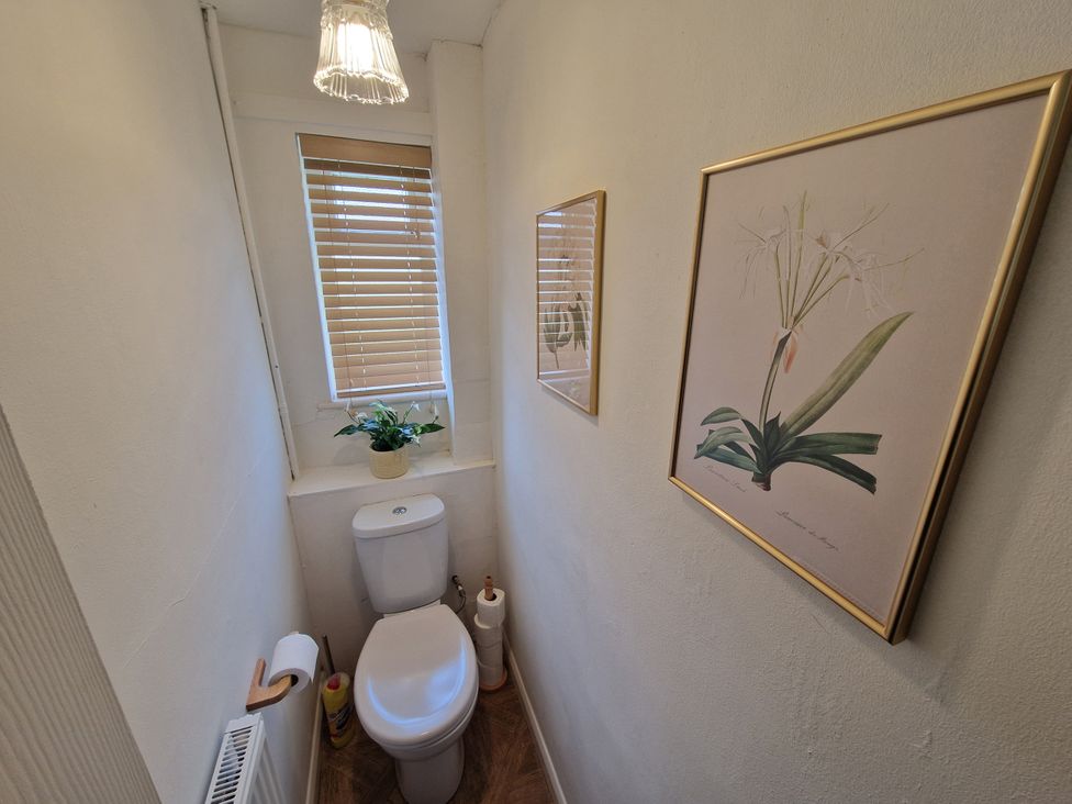 A bathroom with a toilet and wall art at Lake View Cottage Well near Alford