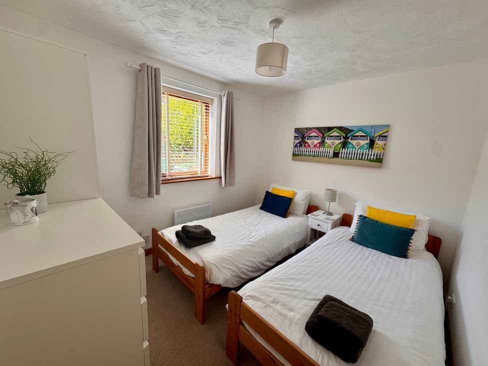 A bedroom with two beds and a bedside table at 220 Cae Du in Abersoch