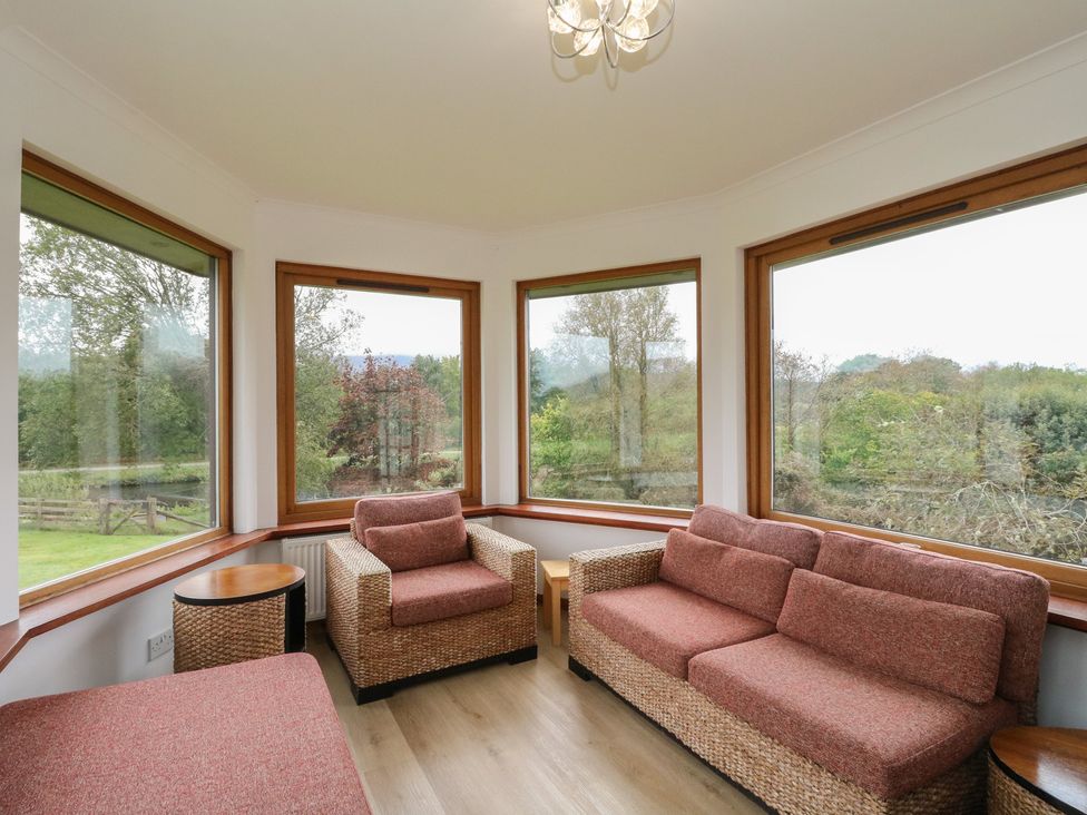 A conservatory with seating and large windows at Maybank in Muirshearlich