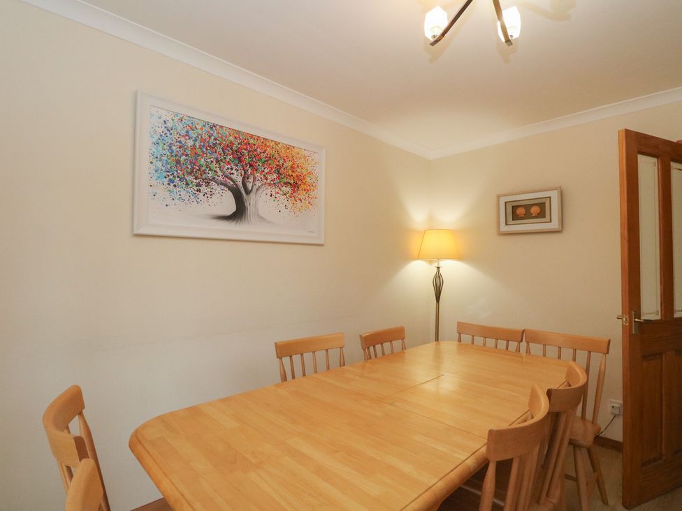 A dining room with a wooden table and chairs at Maybank in Muirshearlich