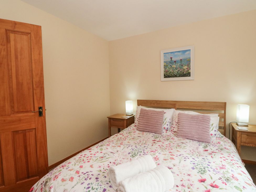 A bedroom with a bed and bedside tables at Maybank in Muirshearlich