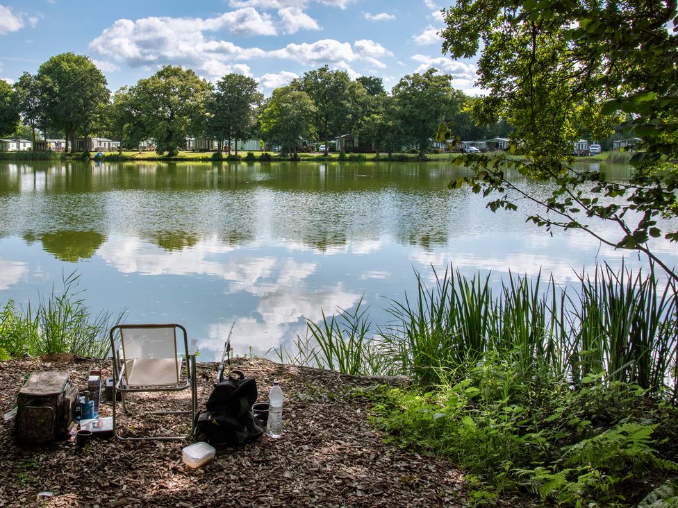A fishing spot beside a lake with a chair and equipment at Owl in Shobdon