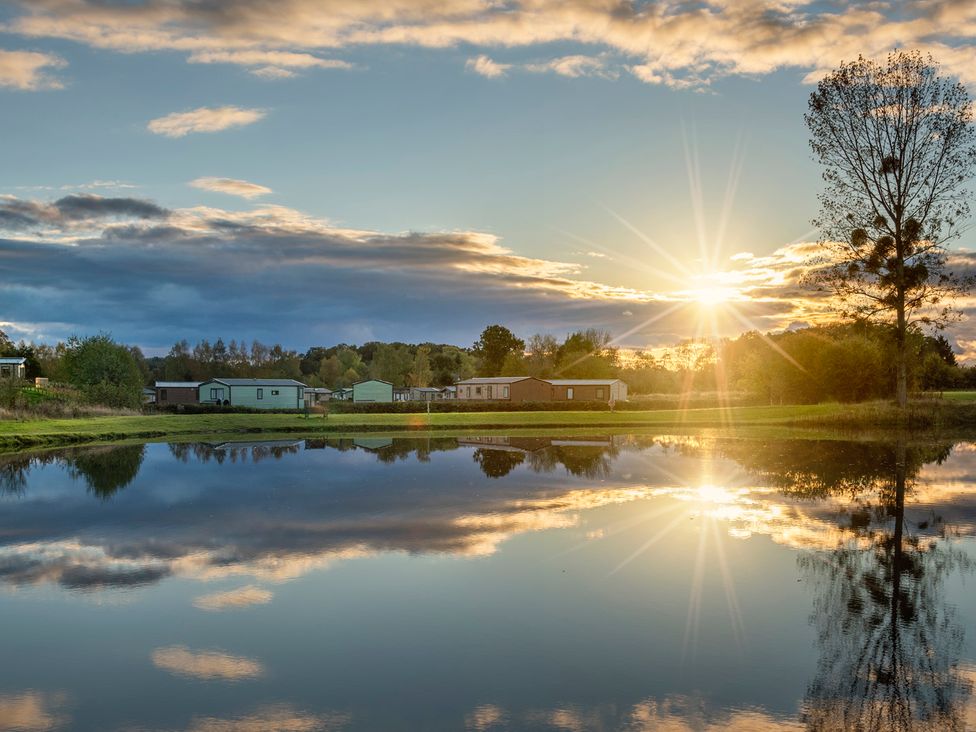 A sunset over a lake with reflections and mobile homes at Owl in Shobdon