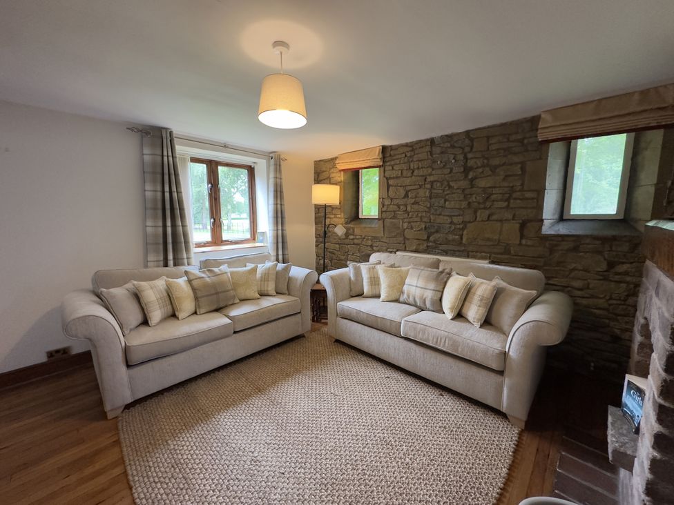 A living room with two sofas and a lamp at Stables Cottage in Shobdon