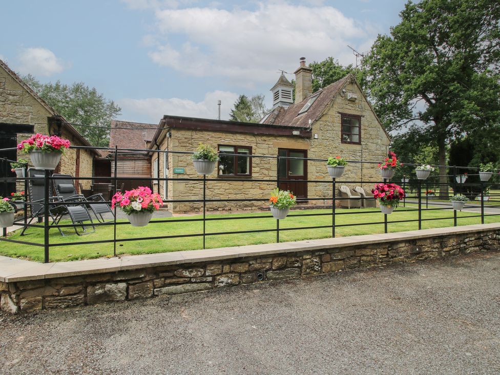 A garden view of a house with planters and chairs at Stables Cottage in Shobdon