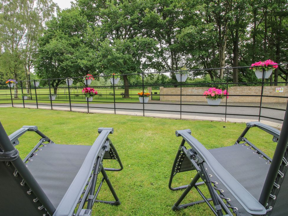 A garden with deck chairs and flower pots at Stables Cottage in Shobdon