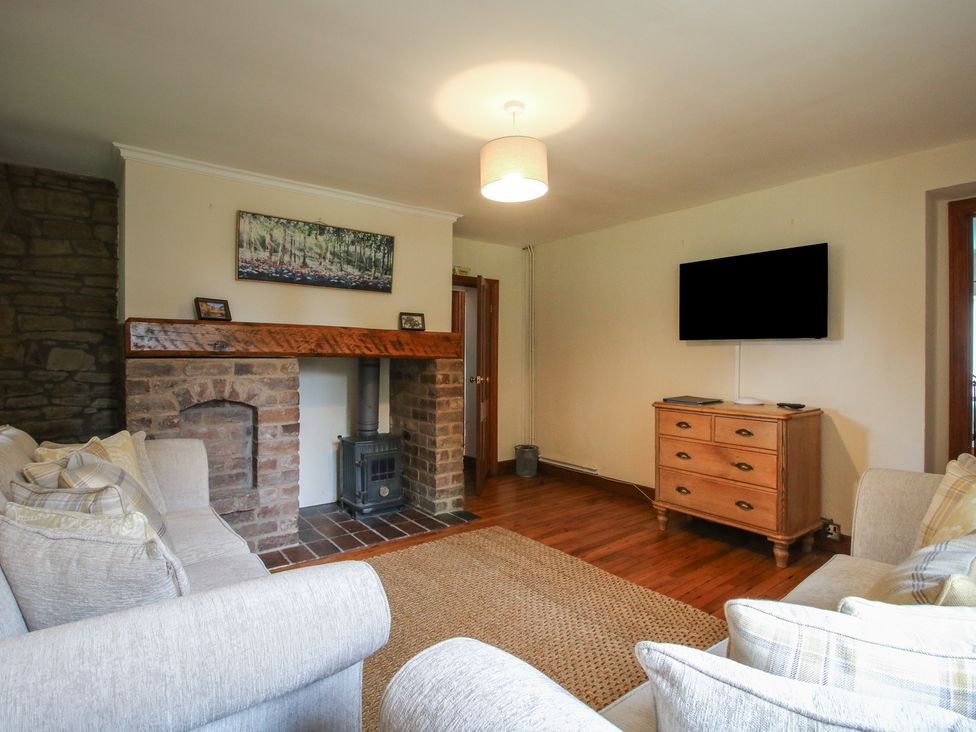 A living room with a fireplace and television at Stables Cottage in Shobdon