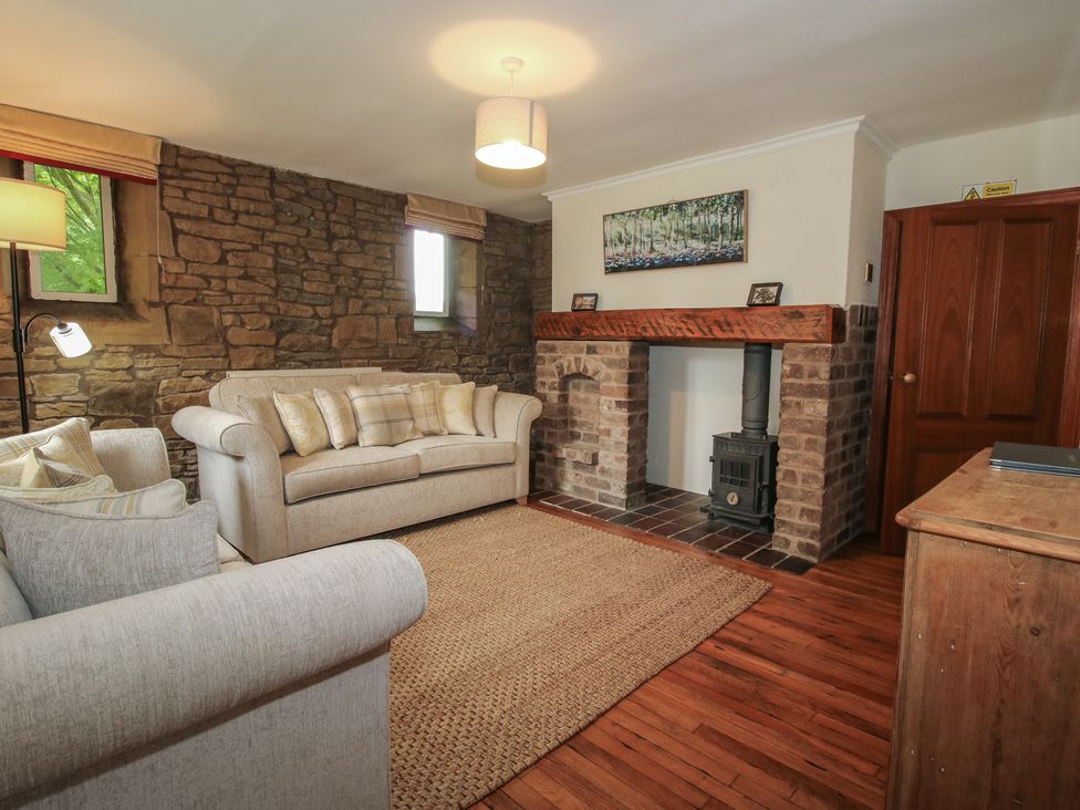 A living room with a sofa and fireplace at Stables Cottage in Shobdon