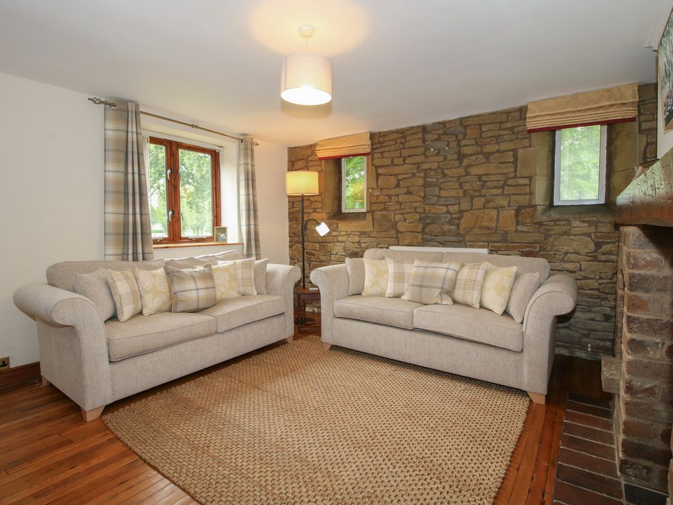 A living room with two sofas and a stone wall at Stables Cottage in Shobdon