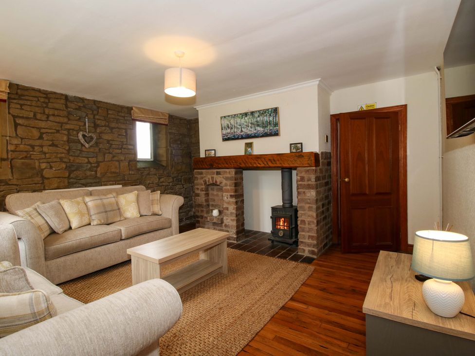 A living room with a fireplace and a sofa at Stables Cottage in Shobdon