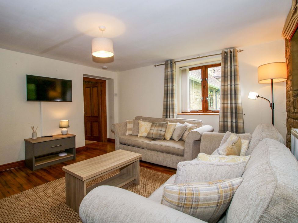 A living room with a sofa, coffee table and television at Stables Cottage in Shobdon