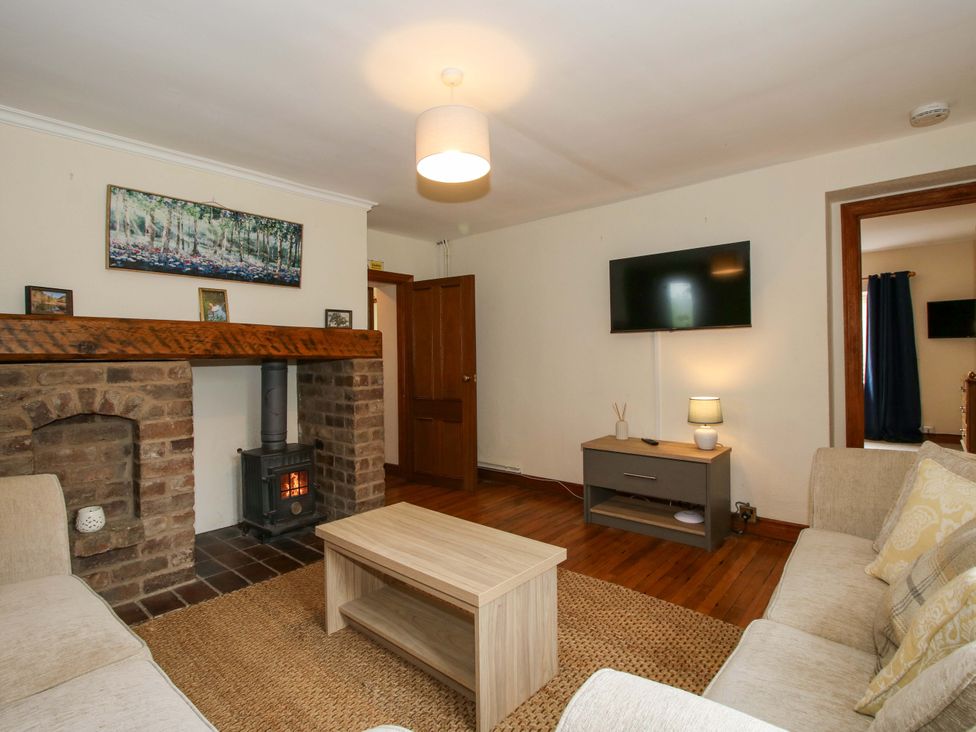A living room with a fireplace and television at Stables Cottage Shobdon