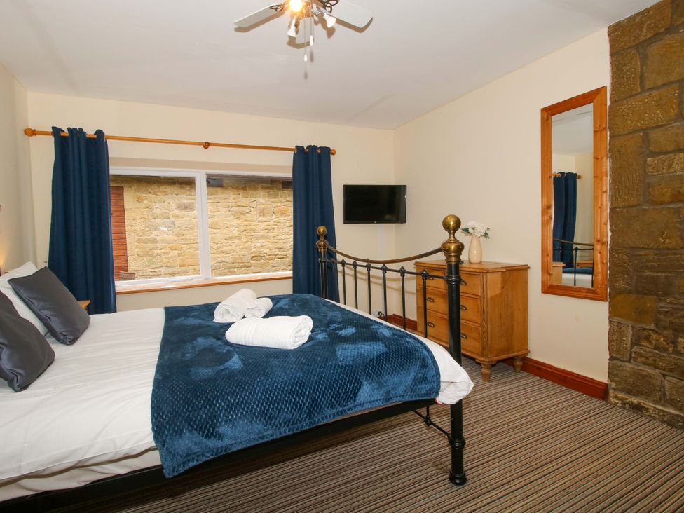 A bedroom with a bed and a mirror at Stables Cottage in Shobdon