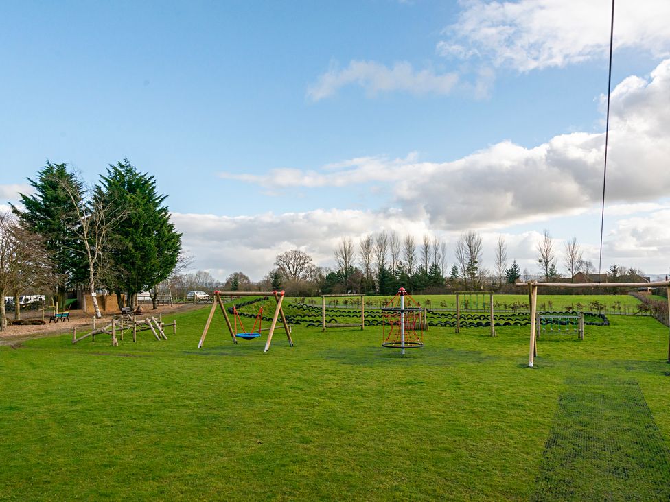 A playground with swings and playground equipment at Stables Cottage in Shobdon