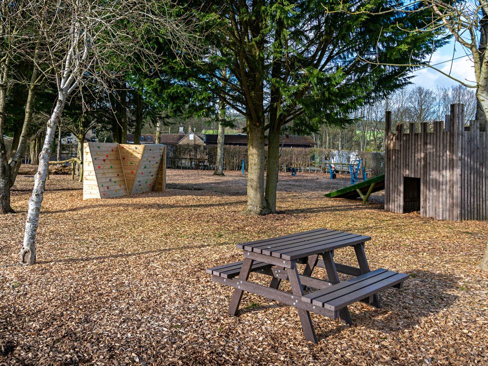 An outdoor play area with a climbing wall and picnic table at Stables Cottage in Shobdon
