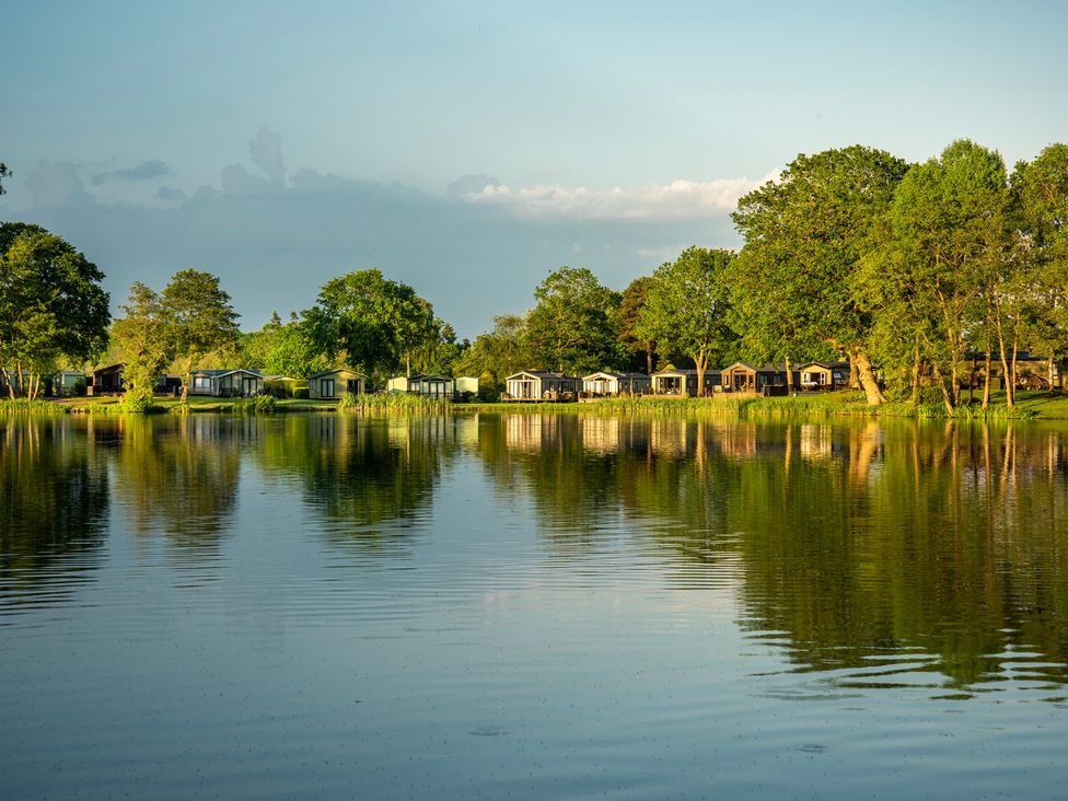 A view of cabins by a lake at Stables Cottage in Shobdon