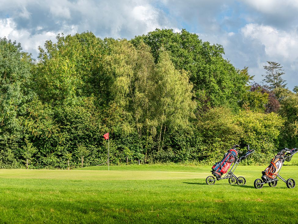 Golf bags on a golf course with a flag at Stables Cottage in Shobdon