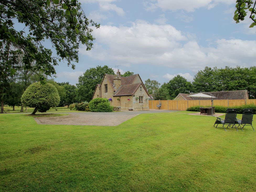 A garden with a house and chairs at Keepers Cottage in Shobdon