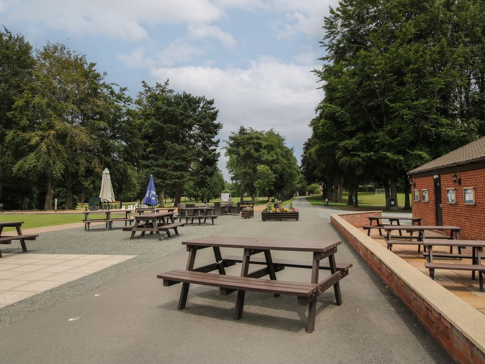 An outdoor seating area with tables and trees at Keepers Cottage Shobdon