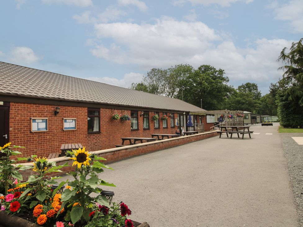 An outdoor area with a building, benches, and flowers at Keepers Cottage in Shobdon