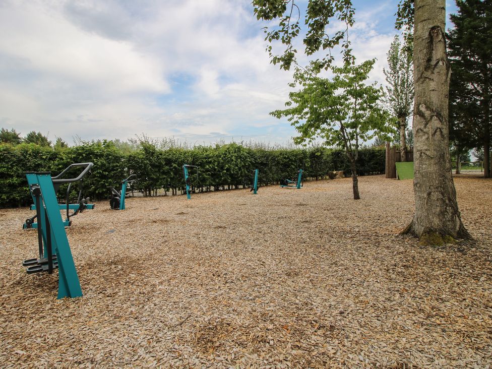 An outdoor exercise area with exercise equipment and trees at Keepers Cottage Shobdon