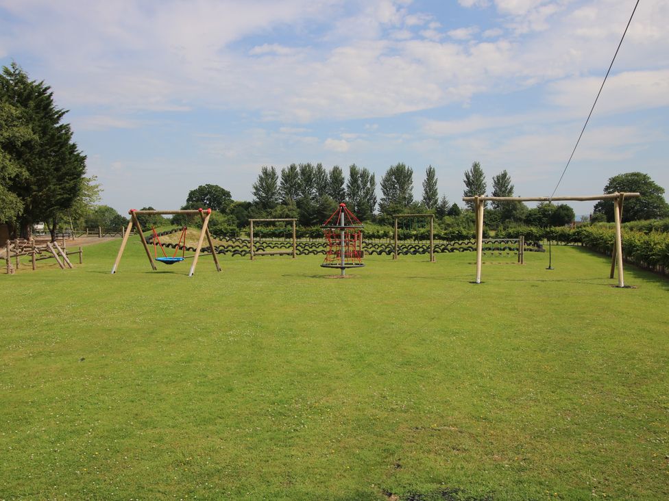 An outdoor playground with swings and a climbing frame at Keepers Cottage in Shobdon