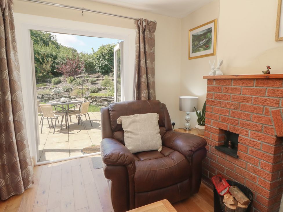 A living room with a chair and a fireplace at Felin Gogoyan in Tregaron