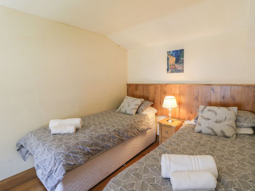A bedroom with two beds and a nightstand at Felin Gogoyan in Tregaron