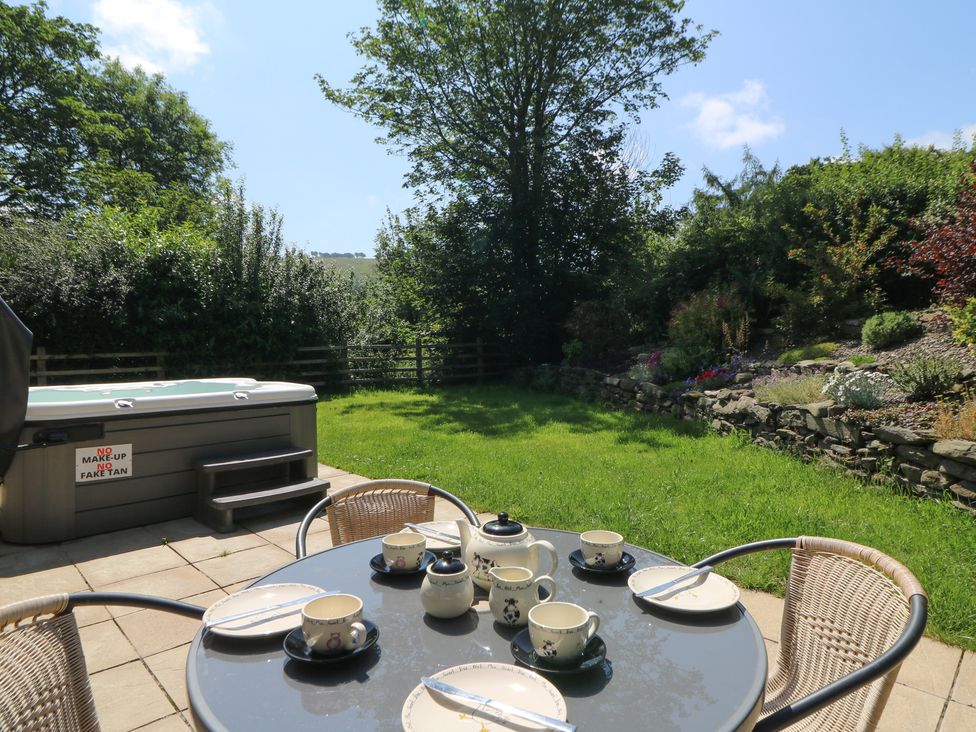 A garden with a hot tub and dining table set for tea at Felin Gogoyan in Tregaron