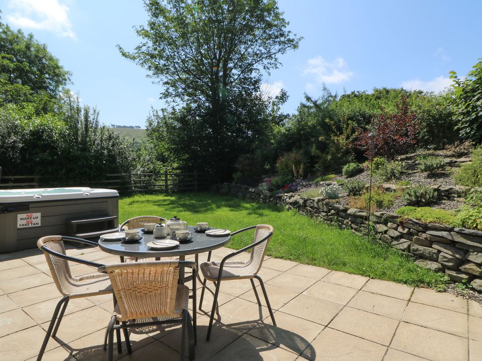 A garden with a table and chairs near a hot tub at Felin Gogoyan Tregaron