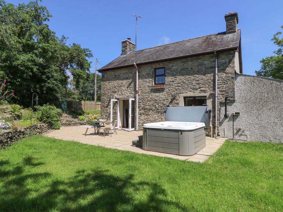 A hot tub and patio area in front of a stone house at Felin Gogoyan in Tregaron