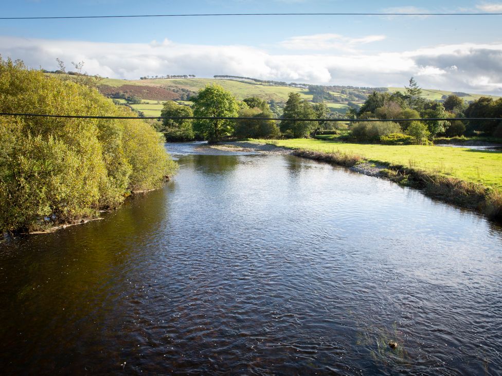 A river surrounded by trees and hills at Felin Gogoyan Tregaron