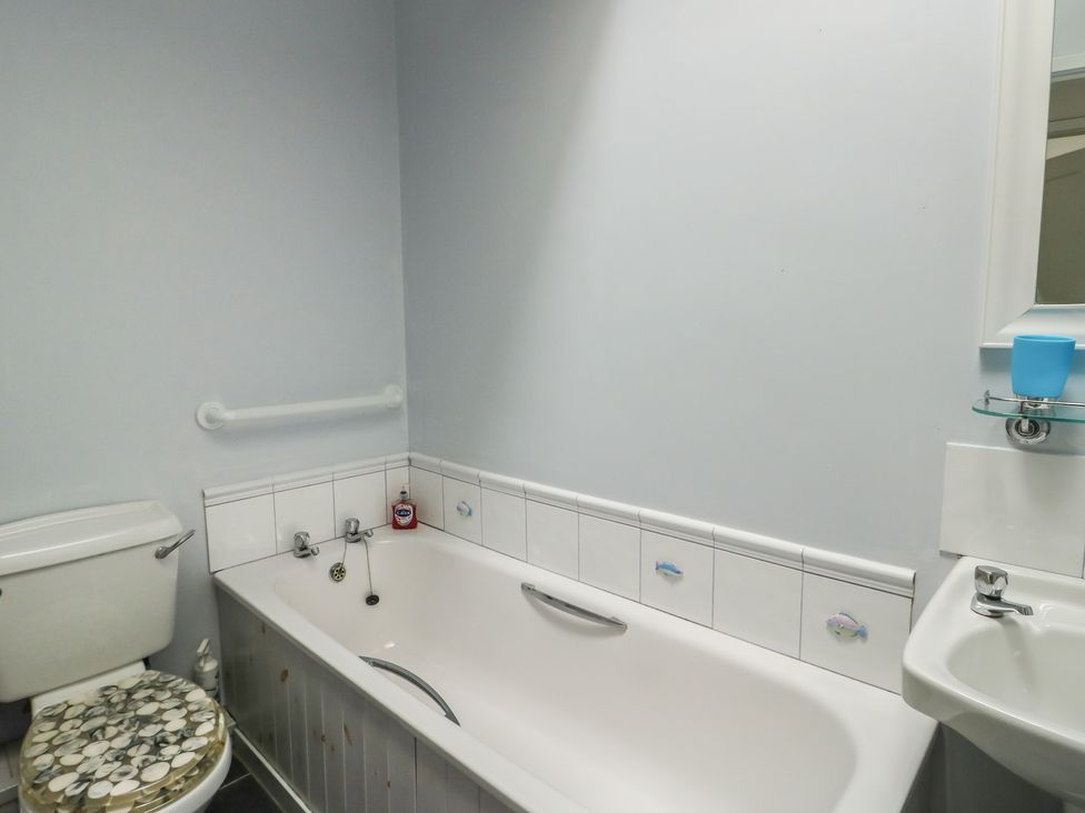 A bathroom with a bathtub, toilet, and sink at 23 Beach Road in Y Felinheli