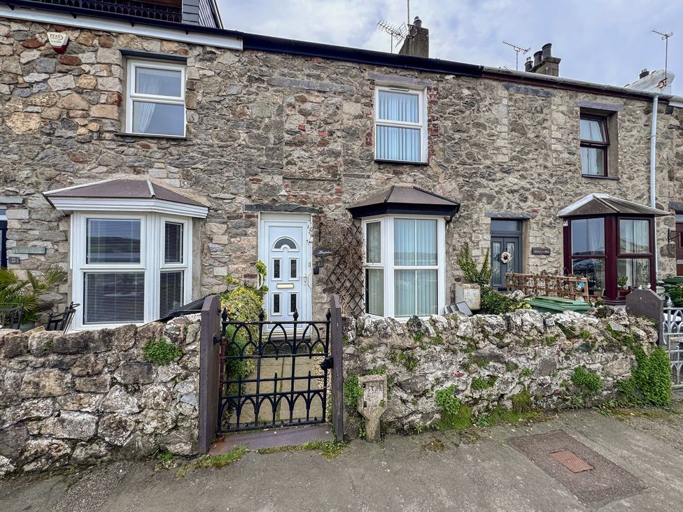 A house facade with a stone wall and gate at 23 Beach Road Y Felinheli