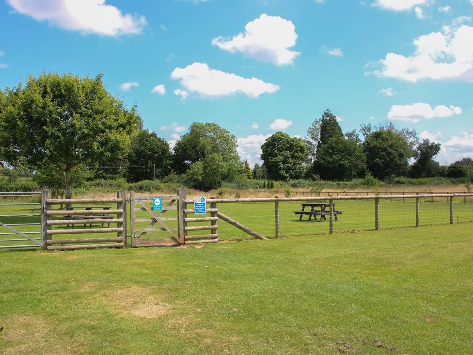 A field with a fence, gate and picnic table at Snowdrop in Eardisland