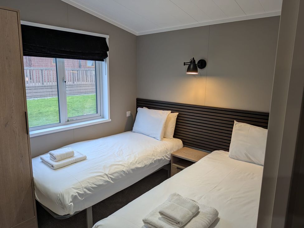 A bedroom with two beds and a window at Snowdrop in Eardisland