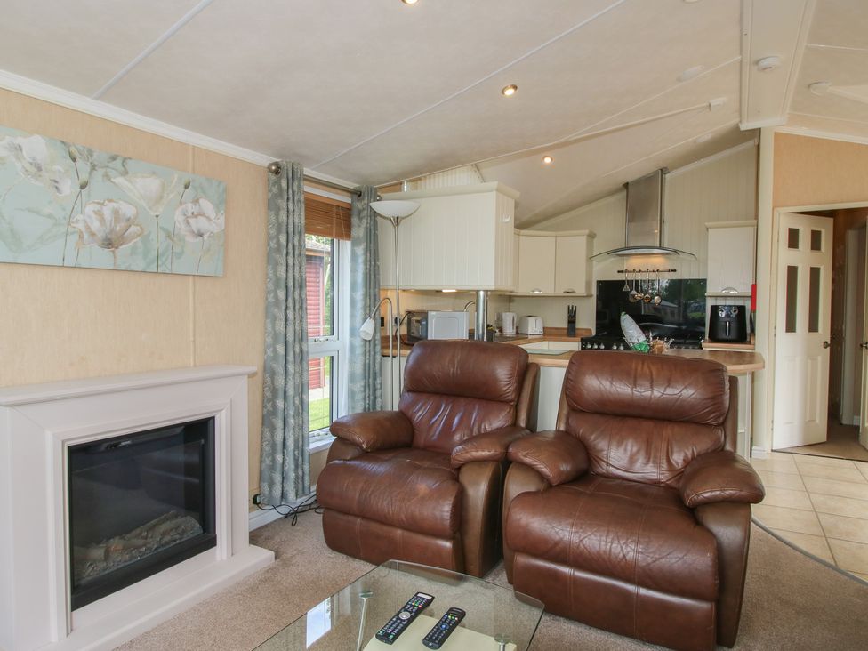 A living room with recliner chairs and kitchen area at Daisy in Eardisland