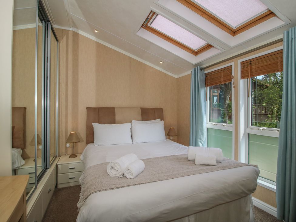 A bedroom with a bed and windows at Daisy in Eardisland