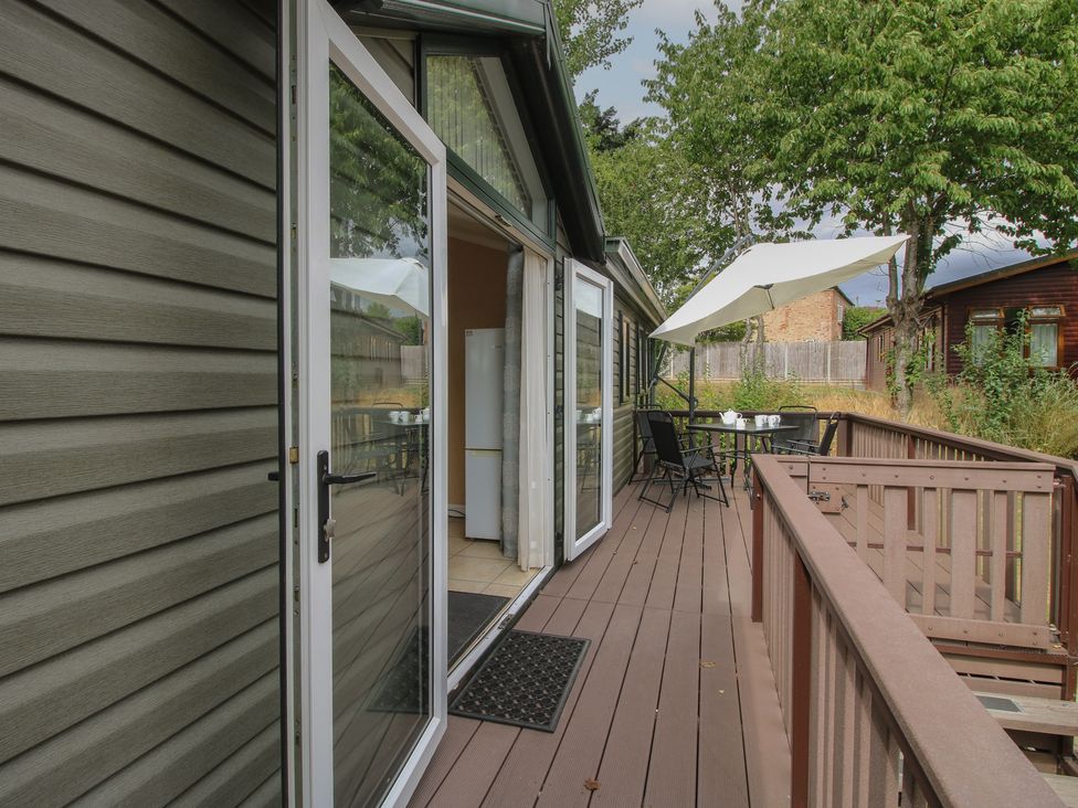 An outdoor deck with a table and chairs at Daisy in Eardisland