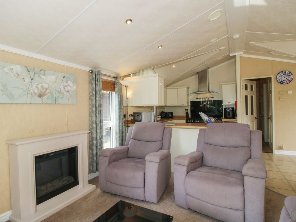 A living room with recliner chairs and a kitchen area at Daisy in Eardisland