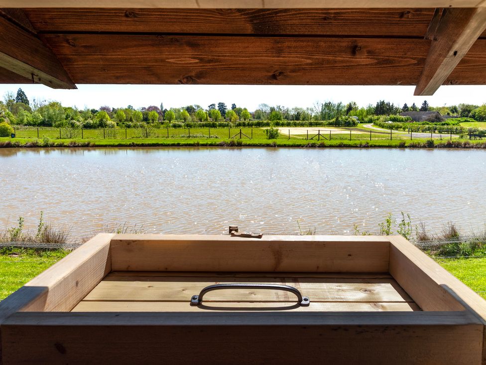 A view of a pond and greenery from a wooden structure at Daisy in Eardisland