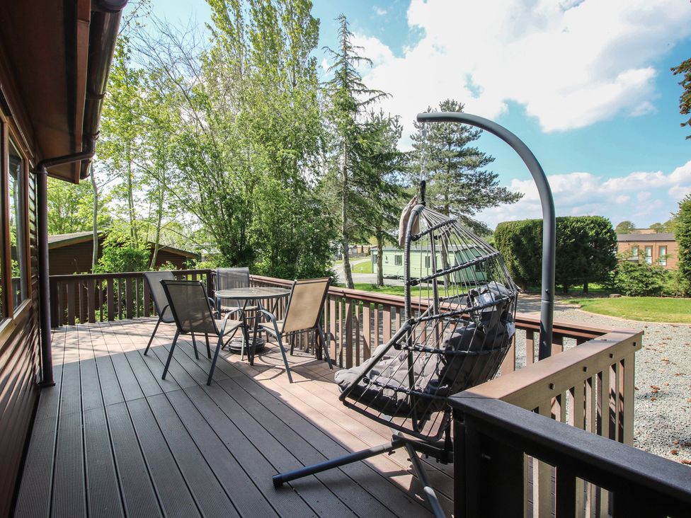 An outdoor deck with a hanging chair and table in Foxglove Eardisland