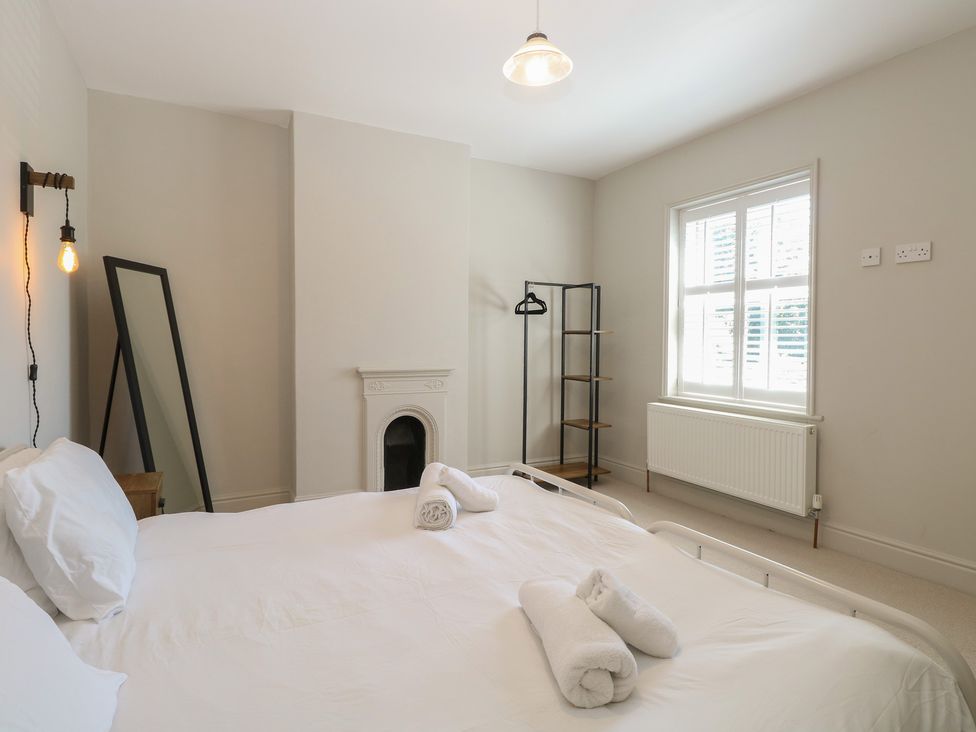 A bedroom with a bed and a mirror at Sunrise House in Pakefield near Lowestoft
